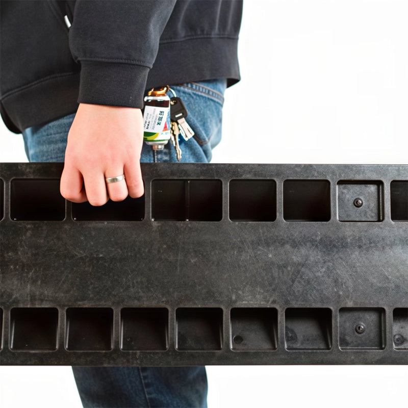 Cargue la imagen en el visor de la galería, Rampa protectora de cables de 2 canales. Persona transportando una rampa protectora de cables portátil de goma negra utilizando las ranuras ergonómicas inferiores.
