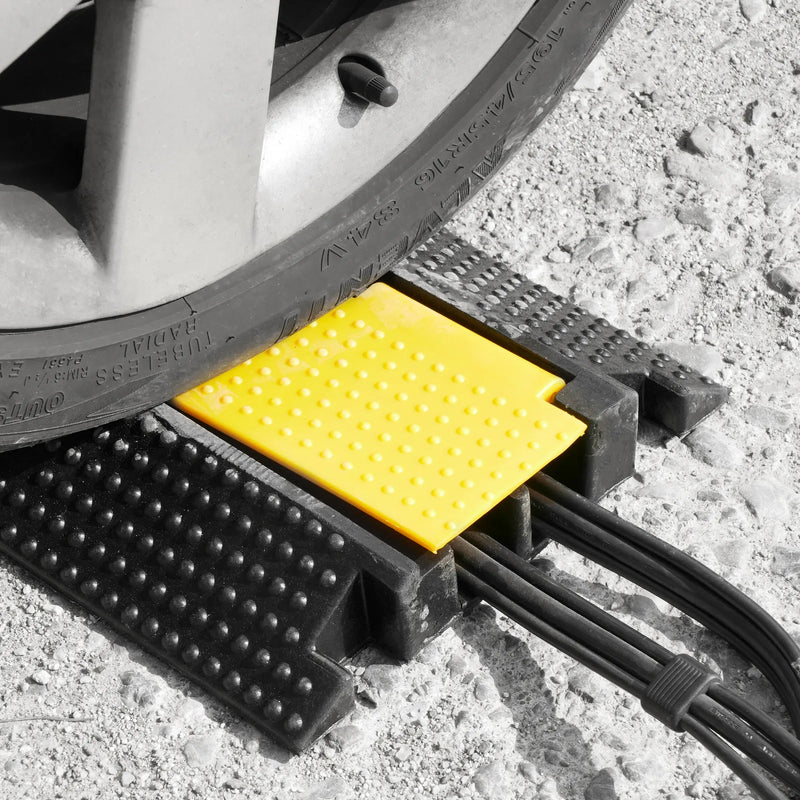 Cargue la imagen en el visor de la galería, Rampa protectora de cables de 2 canales. Rueda de coche pasando sobre una rampa protectora de 2 canales de caucho negro con cables en su interior.
